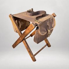 an old wooden folding chair with a bag on it's back and straps attached to the seat