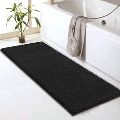 a black bath mat sitting on top of a bathroom floor next to a white tub