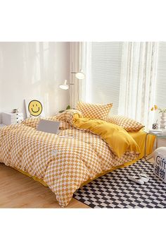 a yellow and white checkered comforter set on a bed in a room with wooden floors