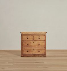 a wooden dresser sitting on top of a hard wood floor next to a white wall