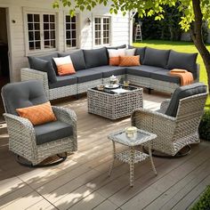 an outdoor living room with grey wicker furniture and orange pillows on the couches