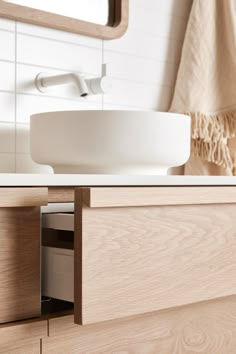 a bathroom sink sitting under a mirror next to a white counter top and wooden cabinets