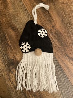 a black and white hat with snowflakes hanging from it's side on a wooden floor