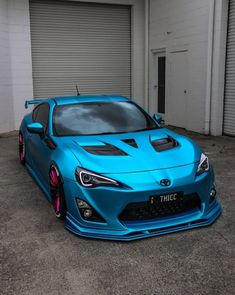 a blue sports car parked in front of a garage