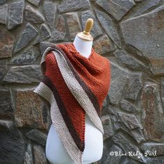 a white mannequin wearing a red and brown striped shawl