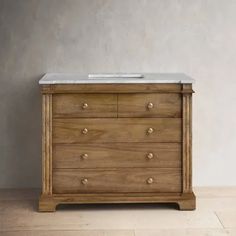 a wooden dresser with two drawers and a white marble top on the bottom, in front of a gray wall