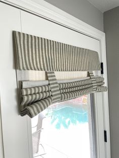 a window that has some curtains hanging on it's side and the blinds are closed