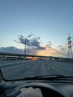 the sun is setting over an empty highway with power lines in the distance and traffic lights on either side