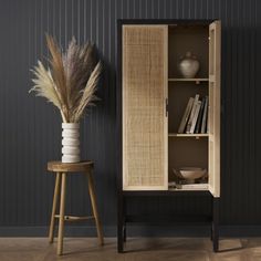 a tall cabinet sitting next to a small table with a vase on top of it