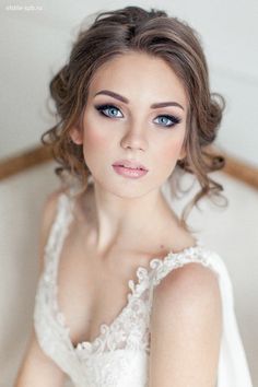 a woman in a white dress with blue eyes and hair is posing for the camera