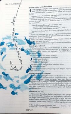 an open bible with blue watercolors and writing on the page, which has been written