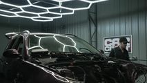 a car being worked on in a garage with two men standing next to the car