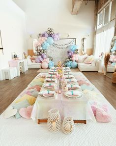 a table set up for a party with pastel colors and balloons on the wall