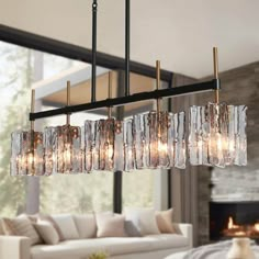 a modern chandelier hanging over a living room table in front of a fireplace