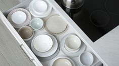 an open drawer filled with dishes on top of a counter