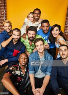 the cast of modern family posing for a group photo in front of an orange wall