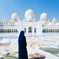 a woman standing in front of a white building with many arches and domes on it