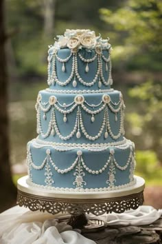 a three tiered blue wedding cake with pearls