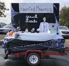 a car with a fake skeleton on the back of it in front of a pharmacy