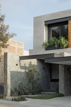 a modern house with plants in the window boxes and concrete walls, along with an asphalt driveway