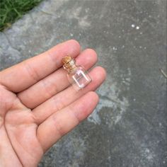 a hand holding a tiny bottle with cork in it