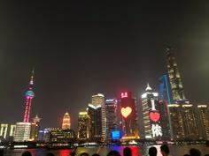 the city skyline is lit up at night with bright lights and buildings in the background