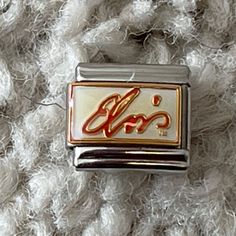 a silver and gold charm with the word love on it's front end sitting on a white blanket