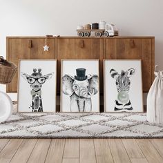 three framed pictures with zebras and giraffes are on the floor in front of a dresser