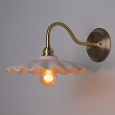 a light that is on the wall next to a white wall mounted lamp with an orange light bulb