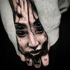 a man's hand with a creepy face painted on it and black ink splatters