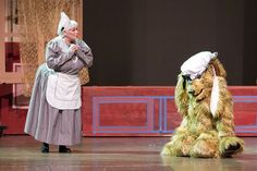 two people in costume standing on stage with one person dressed as a dog and the other wearing a hat