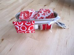 two red and white napkins in a metal basket on a wooden floor with scissors