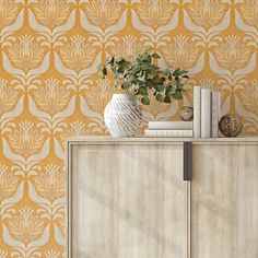 a white vase sitting on top of a wooden cabinet next to a wallpapered wall