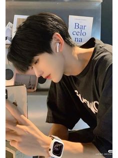 a young man is looking at his cellphone while wearing an apple watch and earbuds