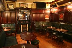 the interior of a restaurant with wood paneling and green leather booths, tables and stools