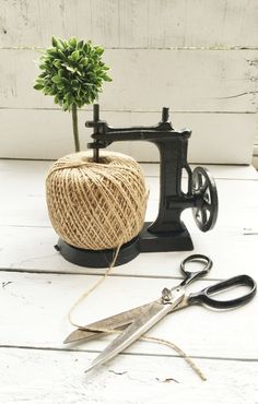 a spool of twine next to an old sewing machine and a small potted plant