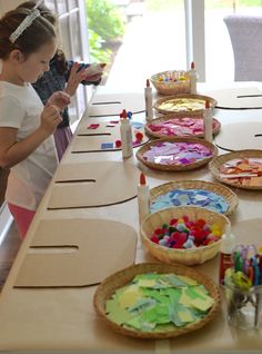 a group of children sitting at a table with paper plates and crayons on it