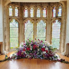 an arrangement of flowers on the floor in front of stained glass windows