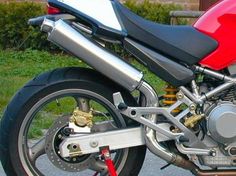 a red and black motorcycle parked on the side of the road next to some grass