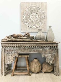 an old wooden table with vases and other decorative items on the shelf next to it