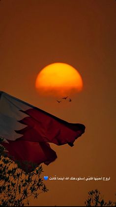 the sun is setting behind a flag flying high in the sky