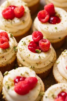 small cupcakes with white frosting and raspberries on top