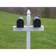 two mailboxes on top of a white post in the middle of a field