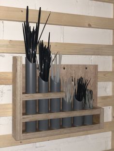 several vases with black and white sticks in them on a wooden shelf next to a brick wall