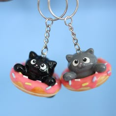 two black cats are sitting on donuts with pink frosting