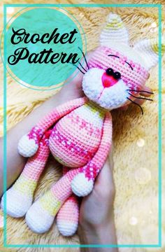 a crocheted pink and white cat sitting on top of a person's hand