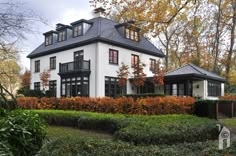 a large white house with lots of windows in the front yard and bushes around it