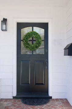 a black front door with a green wreath on it