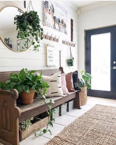 a wooden bench sitting in front of a door with potted plants on top of it