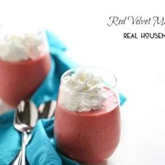 two glasses filled with red velvet milkshake on top of a blue napkin next to silverware